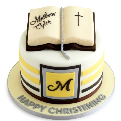 White and yellow Christening cake with an open Bible, cross, and personalised initial.
