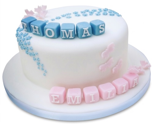 White baby shower cake with blue and pink name blocks, sugar stars, and butterflies.