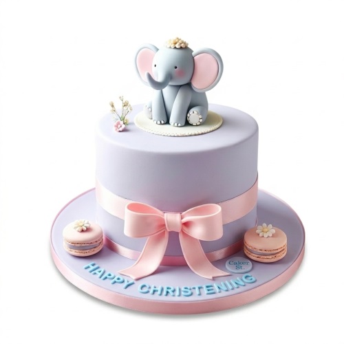 Single tier lavender christening cake with a grey fondant elephant topper, pink ribbon bow, and "Happy Christening" message.