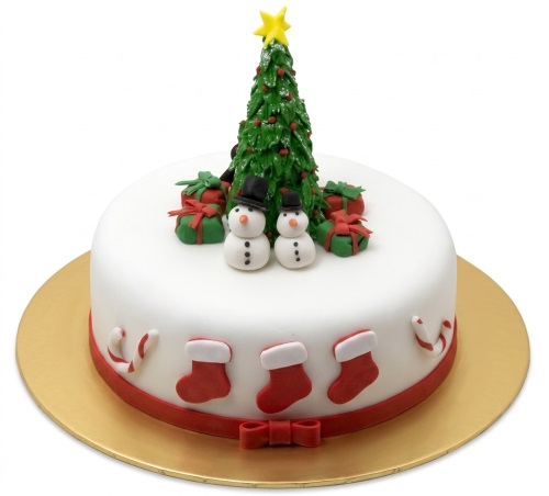 Round white Christmas cake with green Christmas tree, two snowmen, gift boxes, red stockings, and candy canes.