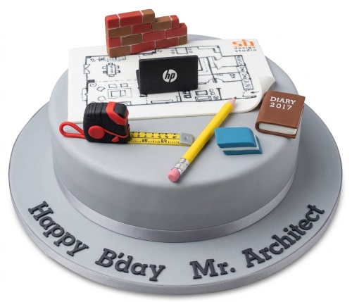 Grey two-tier architect theme birthday cake with edible blueprint, brick wall, measuring tape, and tools.