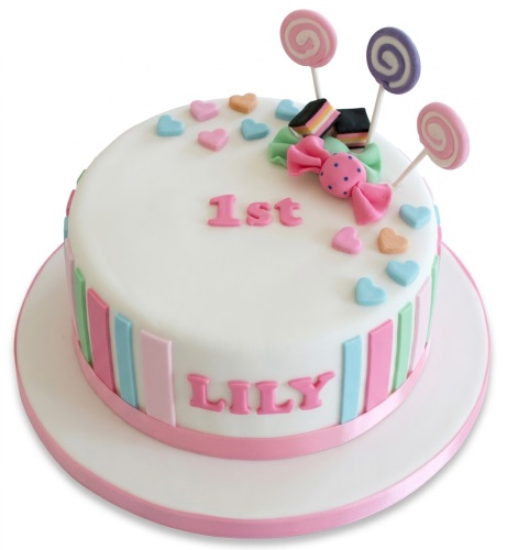 Round white cake with pastel stripes, lollipops, candy bow, hearts, and custom age.