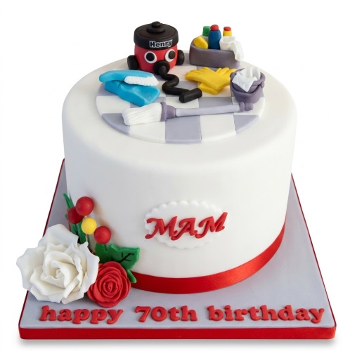 White round birthday cake with Henry Hoover and cleaning supplies on top, decorated with red and white roses.