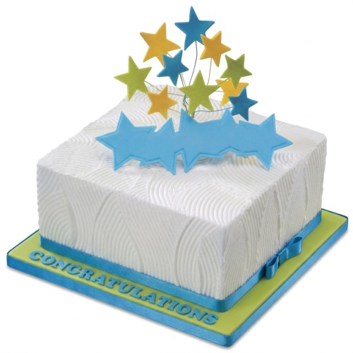 Square white celebration cake with blue, yellow, and green stars and a blue ribbon.