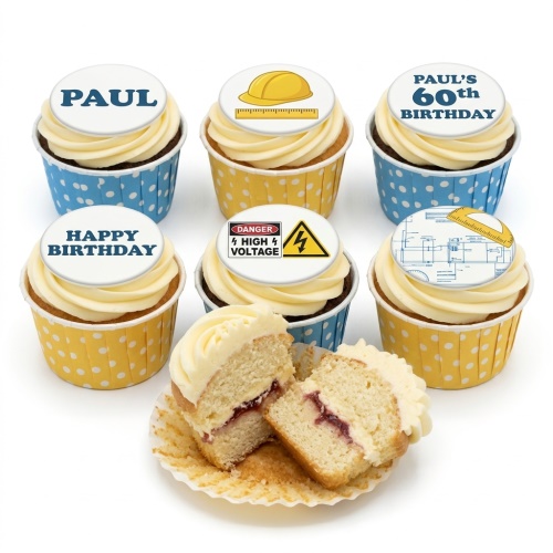 Six construction themed cupcakes with white frosting, yellow and blue polka dot cases, and edible toppers featuring hard hats, blueprints, and a high voltage sign, with one cupcake cut in half.