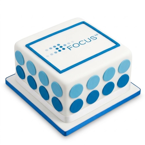 White square cake with blue polka dots and a framed custom logo on top.
