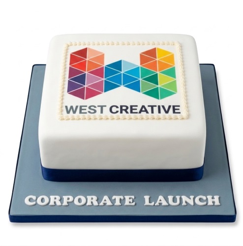White square corporate cake with a multi-coloured company logo and "WEST CREATIVE" text, on a grey board with "CORPORATE LAUNCH".