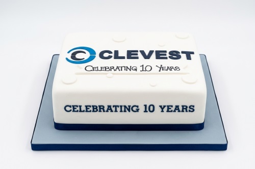 White and blue corporate anniversary cake with "CLEVEST Celebrating 10 Years" message.