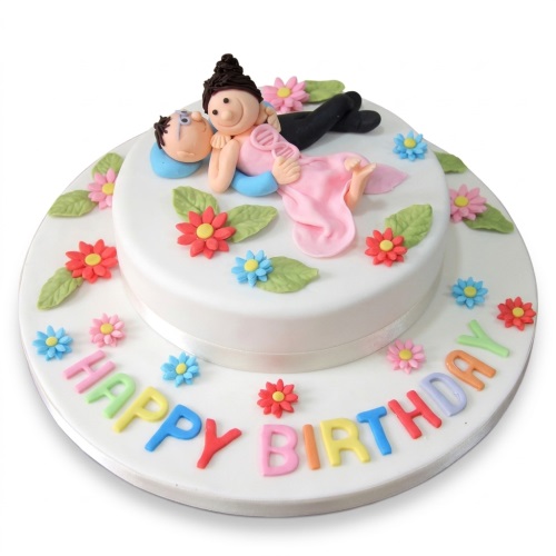 Two-tier white romantic birthday cake with couple figurine, colourful flowers, and "Happy Birthday" message.