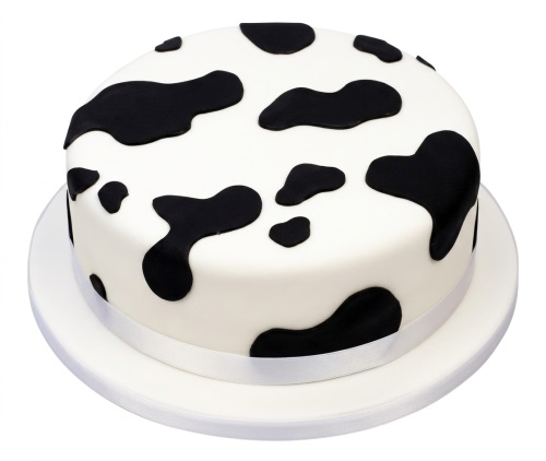 Round white cake with black cow print pattern for a birthday celebration.