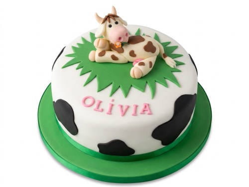 Round white birthday cake with black cow spots, a 3D fondant cow topper, and green grass.