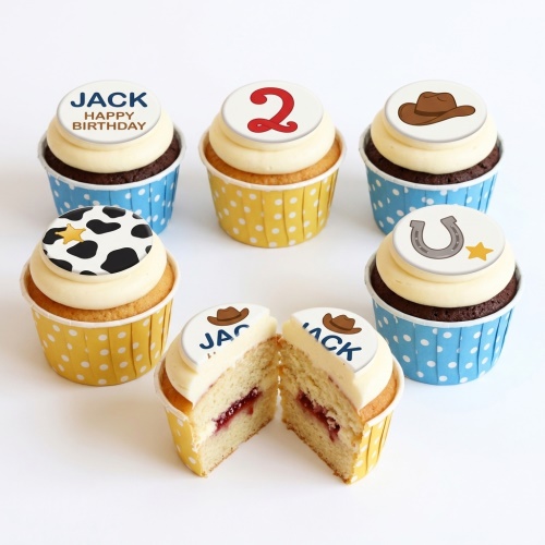 Cowboy themed birthday cupcakes with custom age topper, cow print, hat, and horseshoe decorations.