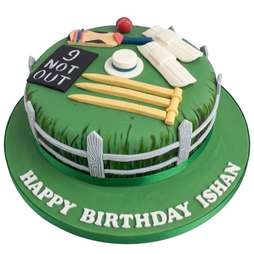 Round green cricket pitch birthday cake with edible bat, ball, stumps, pads, and a white picket fence.