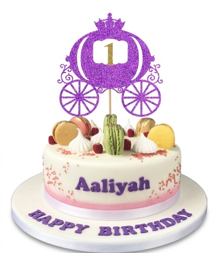 White birthday cake with purple glitter carriage topper, macarons, raspberries, and custom name.