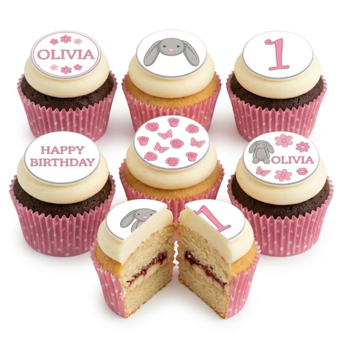 Set of pink and white cupcakes with bunny, butterfly, floral, and custom age '1' toppers.