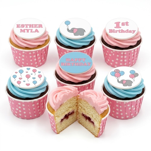 Six cupcakes with pink and blue frosting, topped with edible discs featuring baby elephants, balloons, and hearts. One cupcake is cut open revealing jam filling.