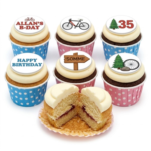 A selection of cupcakes with white frosting and various cycling and adventure themed edible toppers, including bicycles, trees, a signpost, and 'Happy Birthday' message.