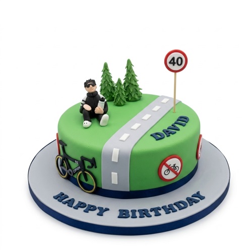 Round green cycling theme birthday cake with a male cyclist figure, road, trees, bicycle, and custom age sign.