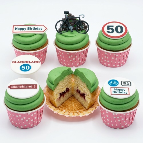 Green frosted cupcakes with cycling theme decorations, including a bicycle model and road sign toppers.