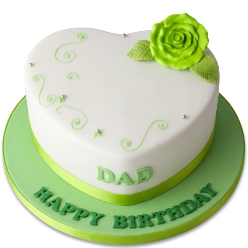 White heart shaped birthday cake with green sugar rose, swirls, and personalised message.