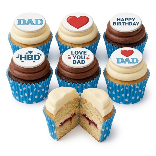 A selection of vanilla and chocolate cupcakes in blue polka dot wrappers, topped with "DAD", "HBD", "LOVE YOU DAD" and red heart messages. One cupcake is cut in half, showing a jam filling.