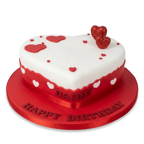 Heart-shaped red and white birthday cake with red hearts and glitter toppers, featuring a red ribbon.
