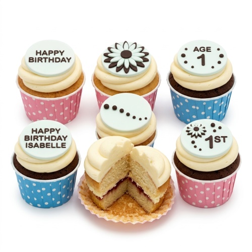 Assortment of birthday cupcakes with white frosting, light blue custom age and name toppers, and floral decorations.