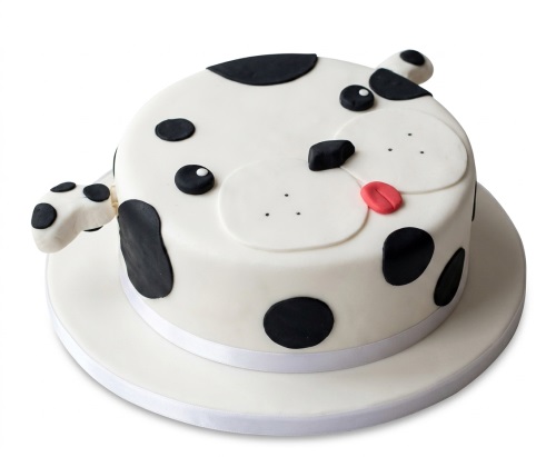 White and black spotted dog face birthday cake with black ears, nose, and a red tongue.