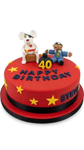 Red birthday cake with Danger Mouse and Penfold figures, yellow stars, and a custom age bomb decoration.