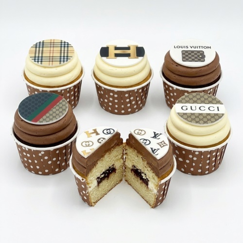 Assortment of designer brand logo cupcakes with cream and chocolate frosting in polka dot wrappers.