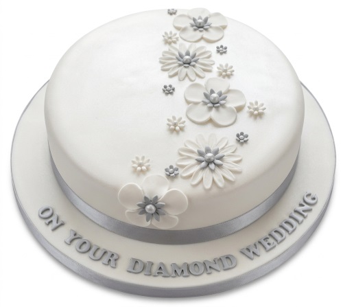 Round white cake with silver ribbon and white and silver sugar flowers, for a Diamond Wedding Anniversary.