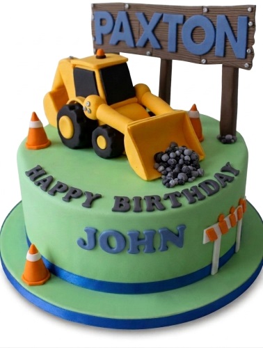Round green birthday cake with a yellow digger, traffic cones, and a construction sign.