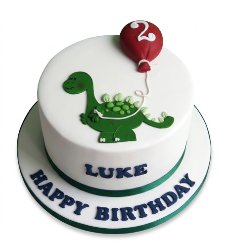 White round cake with a green cartoon dinosaur and a red balloon custom age topper, with a personalised name and 'Happy Birthday' message.