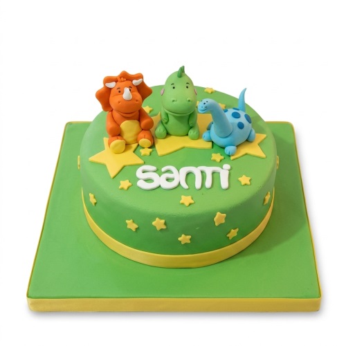 Green round birthday cake with three colourful dinosaur figures, yellow stars, and a personalised name.