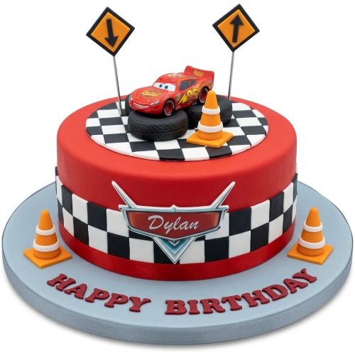 Red single-tier cake with Lightning McQueen car, tires, traffic cones, and checkered flag pattern.