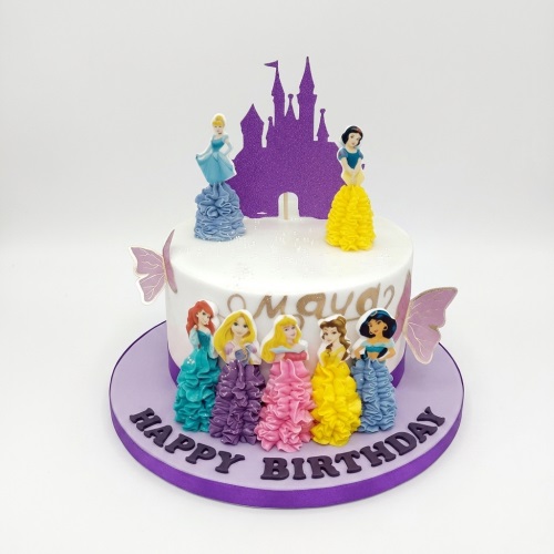 White single-tier princess birthday cake with purple castle topper, multiple princess figurines, and butterfly decorations on a purple cake board with a 'Happy Birthday' message.