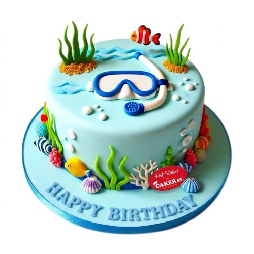Round light blue cake with snorkel mask, clownfish, yellow fish, coral, and seaweed decorations.