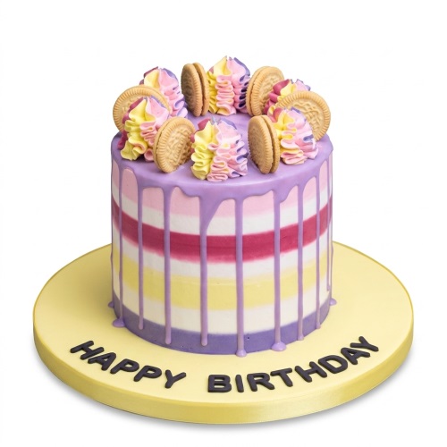 Colourful striped birthday cake with purple drip, cream swirls, and cookie decorations on a yellow board.