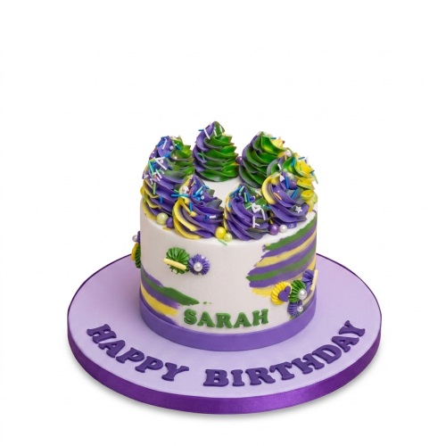 Round white birthday cake with purple, green, yellow swirls, piped buttercream, and sprinkles.