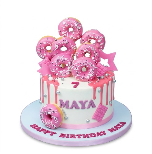 White birthday cake with pink drip, topped with pink doughnuts, sprinkles, stars, and chocolate bars. Includes a custom age and name.