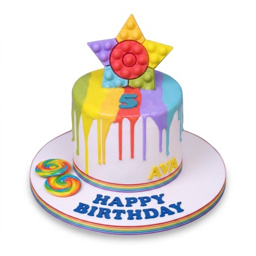White birthday cake with rainbow drips, a star Pop It toy topper, and rainbow swirl lollipops.
