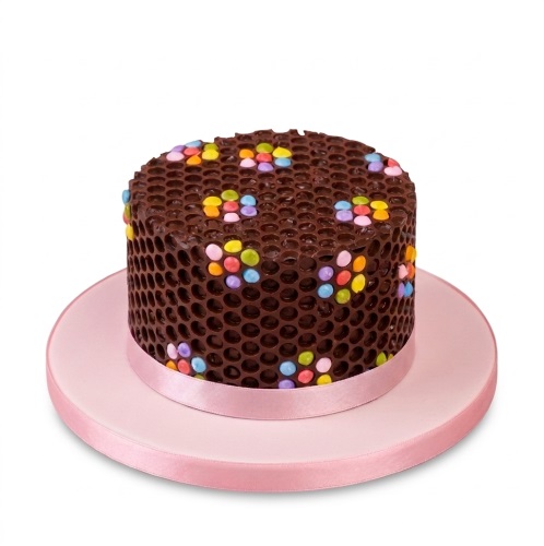 Round chocolate honeycomb cake with colourful candy dots and pink ribbon.