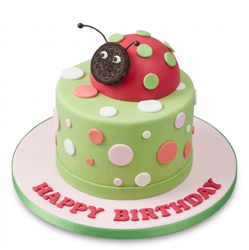 Green single-tier birthday cake with pink, white, and green polka dots, topped with a red ladybug with an Oreo head.