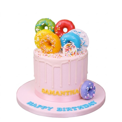 Pink drip birthday cake topped with colourful miniature doughnuts and sprinkles, with a personalised name and message.