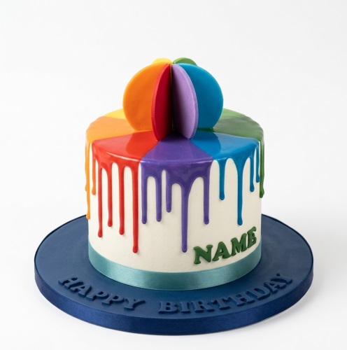 Round white cake with rainbow drip and spherical rainbow topper, on a blue board with 'Happy Birthday' embossed.