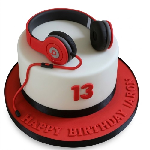 Round white birthday cake with red and black headphones, custom age, and personalised message.