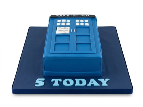 Blue TARDIS shaped birthday cake with a custom age message on a dark blue board.