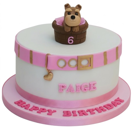 White fondant cake with a cute puppy in a basket, pink belt, and custom age topper.