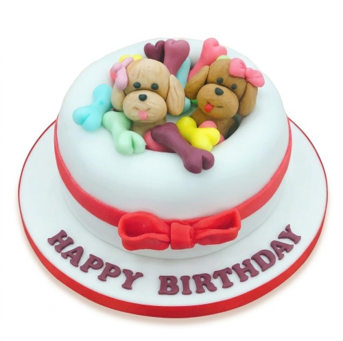 White round birthday cake with two fondant puppies and colourful bones.