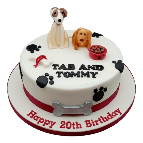 Round white birthday cake with two dog figurines, paw prints, and a custom message.